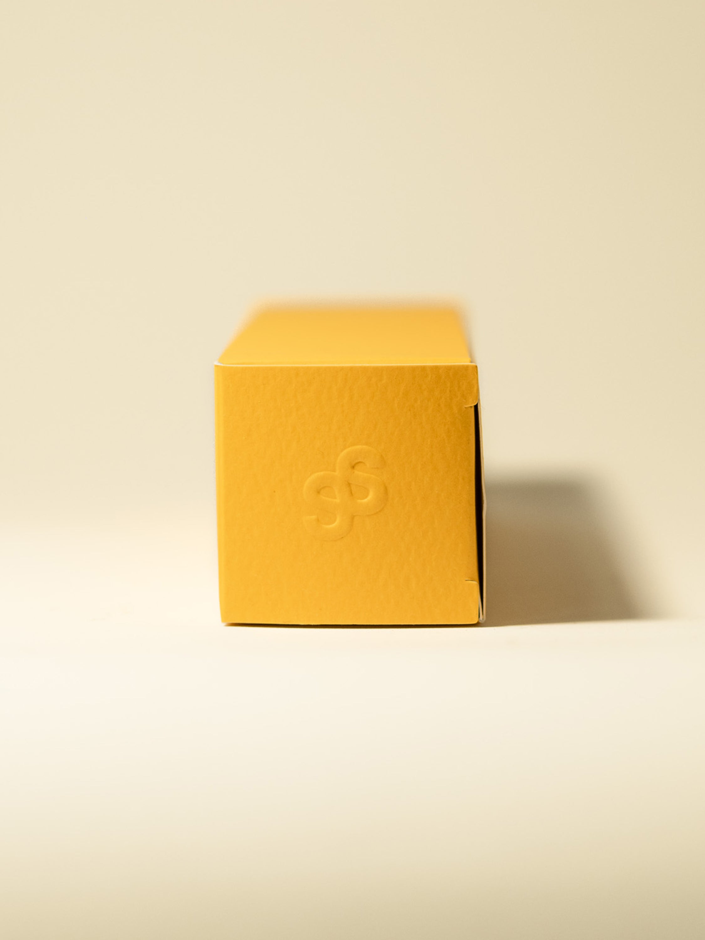 Sancta Solis Nourishing Body Oil Secondary Box Packaging. Blind emboss logo on yellow box.